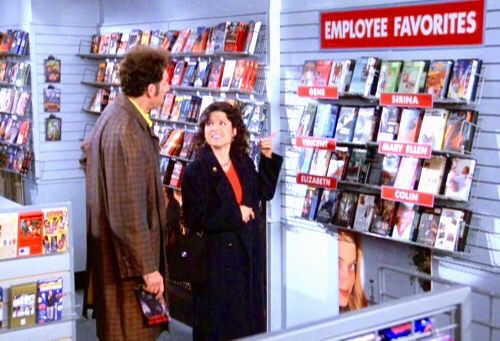 Image from Seinfeld with Kramer and Elaine looking at Employee Favorites wall of movies