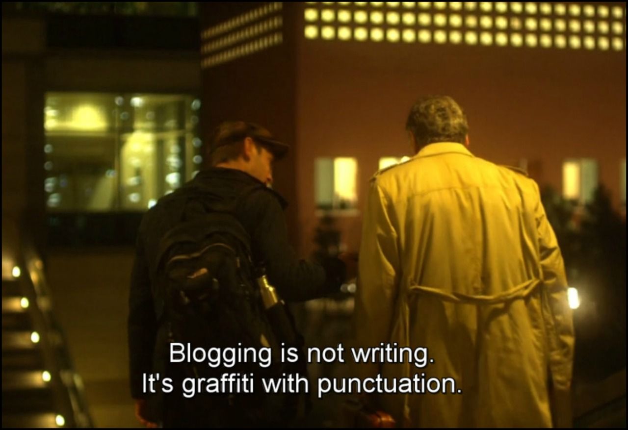 Image of two men's back as they are talking with subtitles: "Blogging is not writing. It's graffiti with punctuation."